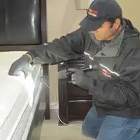 Bed bug inspection technician checking a mattress and bed frame for signs of infestation in Saint Petersburg, FL