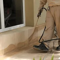 General pest control technician spraying exterior perimeter around a home in Saint Petersburg, FL