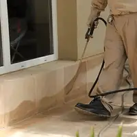 General pest control technician spraying exterior perimeter around a home in Saint Petersburg, FL