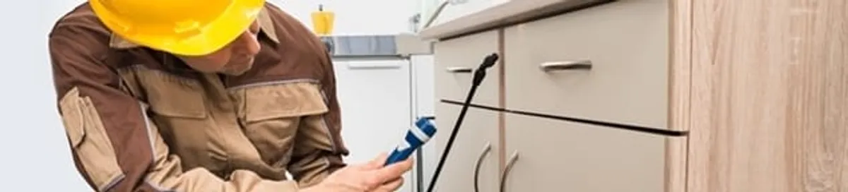 Roach exterminator applying treatment under kitchen cabinets in Saint Petersburg, FL